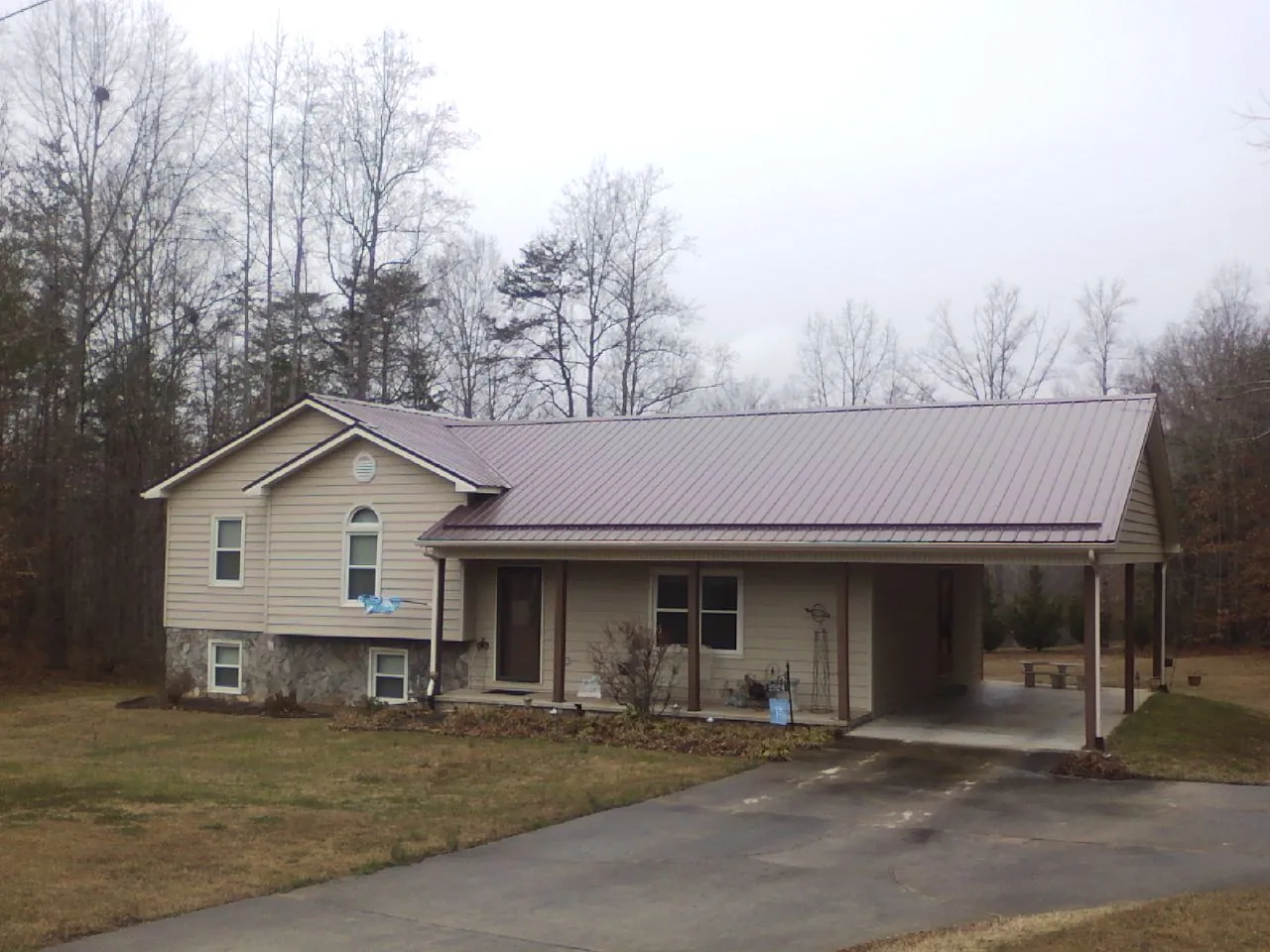 Burgundy metal roof on a tan split level home with an attached carport in Chestnut Hill