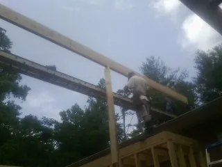 Carpenter setting a ridge beam over a new addition frame — Ice Dam Removal by Roofing Brothers in Chestnut Hill