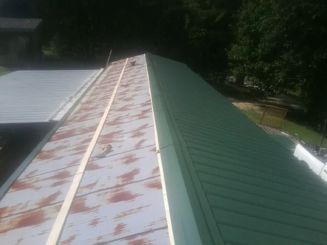 Old rusted panels beside newly installed green metal roofing — Wind Damage Roof Repair by Roofing Brothers in Chestnut Hill