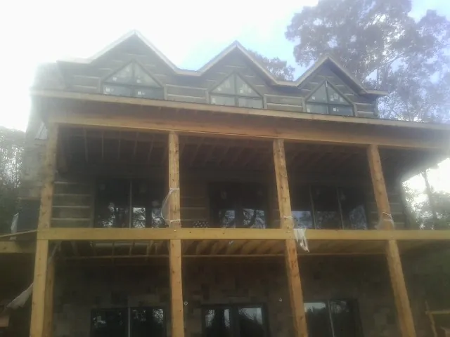 Dormers and porch framing on a large log home under construction — Roof Coating work by our crew in Chestnut Hill