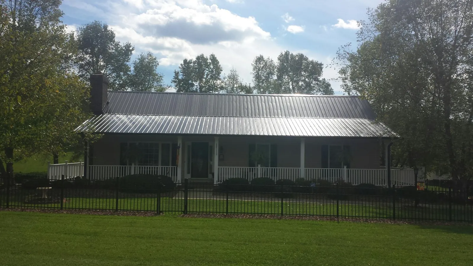 Gray metal roof on a brick ranch with a full width front porch — Gutter Guard Installation work by our crew in Chestnut Hill