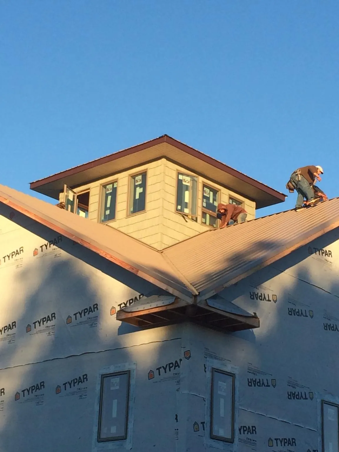 Roofers working around a rooftop cupola on a new metal roof at sunset — Roof Waterproofing in Chestnut Hill by Roofing Brothers